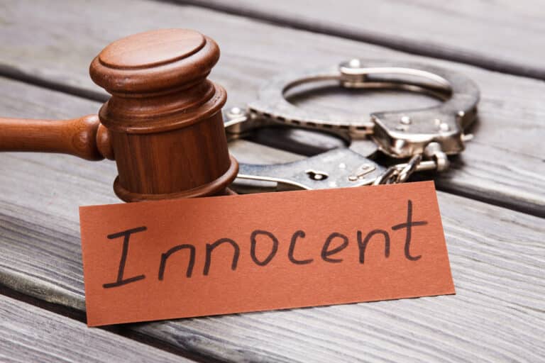 Wooden gavel and handcuffs followed by “innocent” inscription, making the impression of a wrongful accusation.