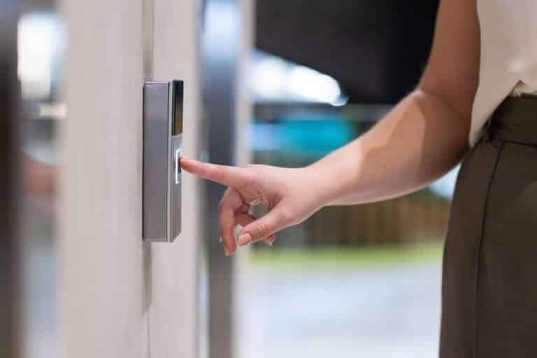 Close-up of a person pressing a smart doorbell button outside a home.