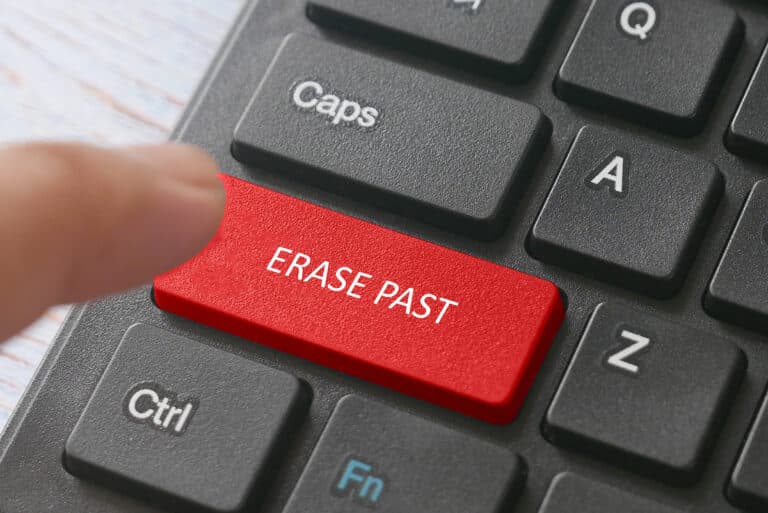 A finger clicking the ERASE PAST button on a keyboard, symbolizing a fresh start.