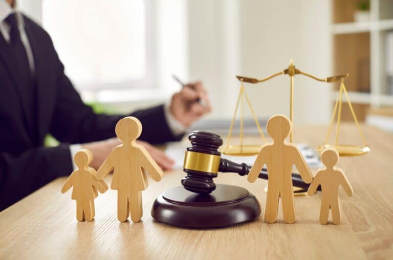 Little wooden figures of parents and children placed on desk in courthouse symbolizing divorce