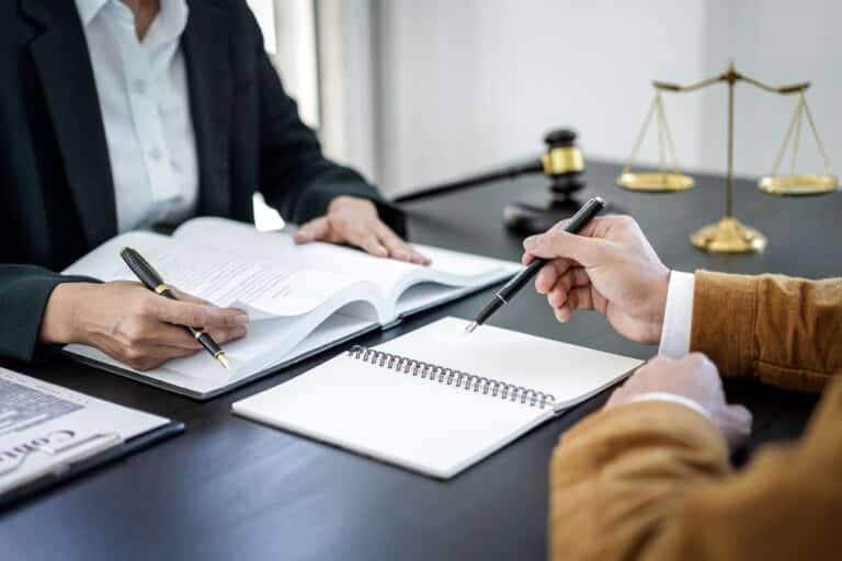 Two people sitting and reviewing documents, with open books, a contract, and a notepad between them, symbolizing trusted legal counsel and family law consultation.