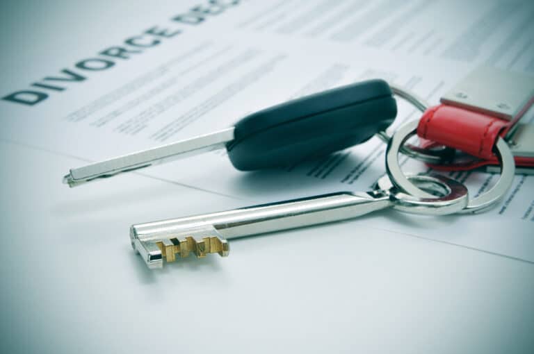 House key and car key on top of divorce paperwork, symbolizing division of marital property in North Carolina.